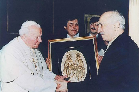 Fethullah Gülen en de paus houden samen een ingelijste icoon vast, met twee mannen erachter